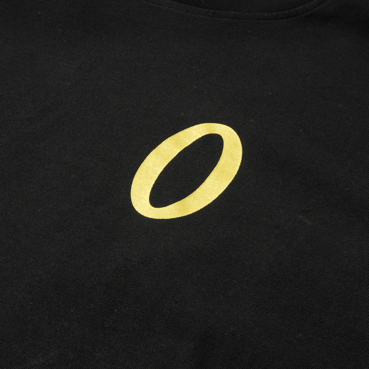 Close-up of gold embroidered "O" logo on black fabric