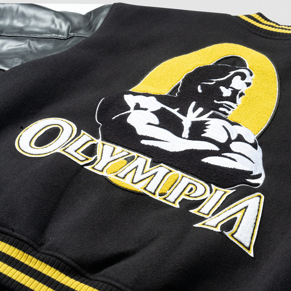 Olympia Champions Gold Varsity Jacket in Black – Front Logo Close-Up