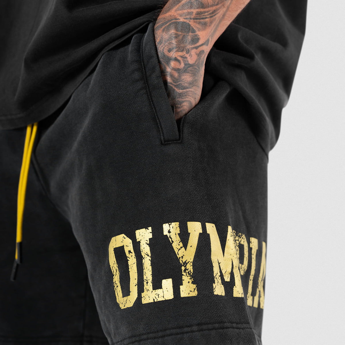 Close up of the Joes Olympia Sweatshort side pocket in use and the "OLYMPIA" wordmark logo below the pocket