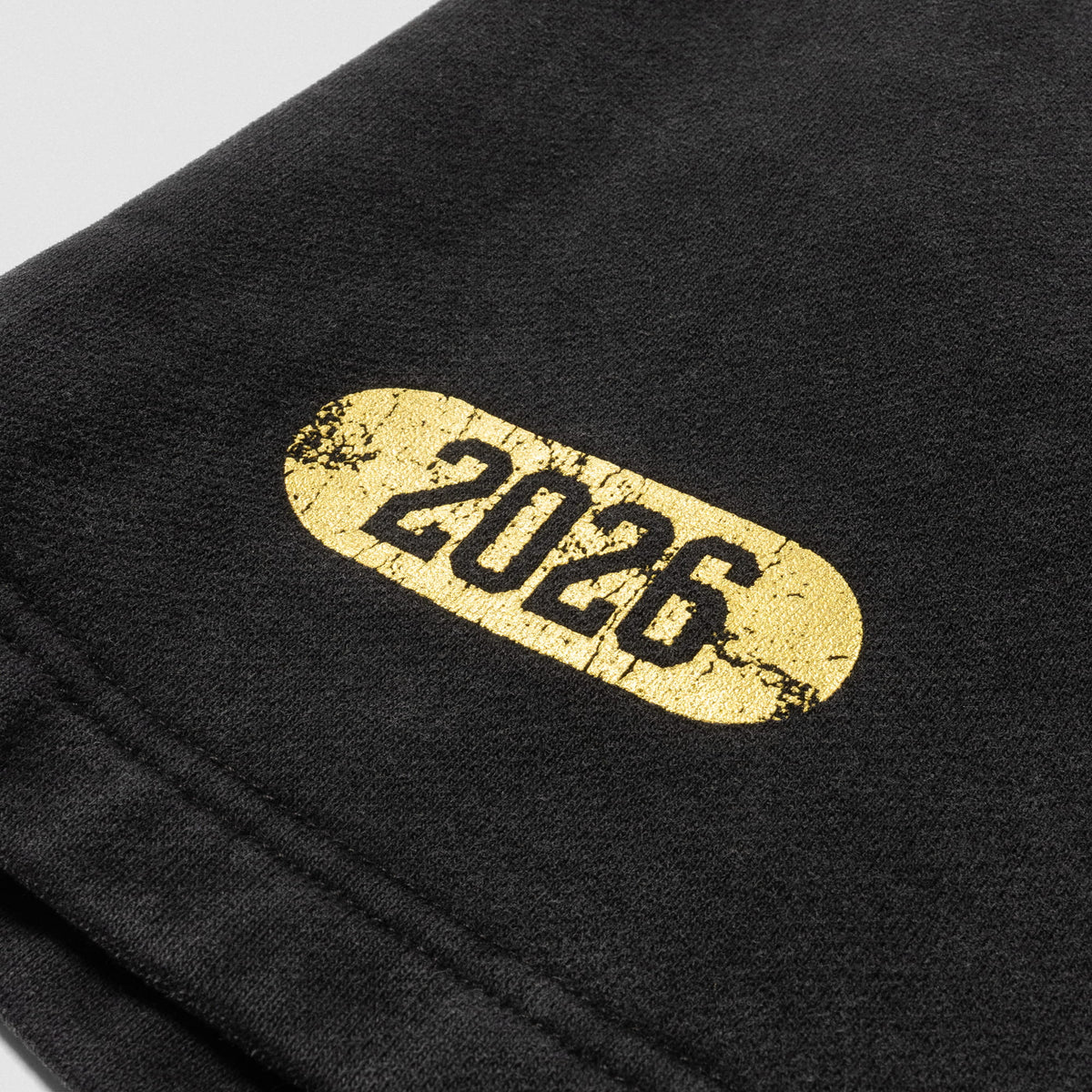 Close up of the "2026" distressed logo found on the hem of the Joes Olympia Sweatshort