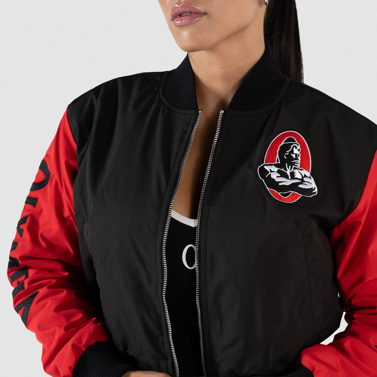 Signature Crop Bomber Jacket | Close up of unzipped black and red jacket with classic Olympia logo on the chest