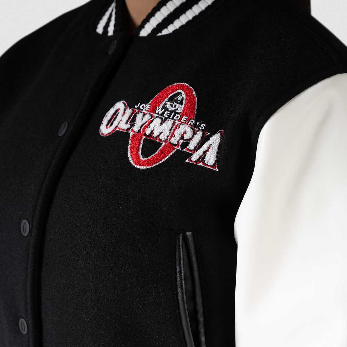 Signature Crop Varsity Jacket | Left chest graphic feature of the Joe Weider's classic Olympia bodybuilding logo