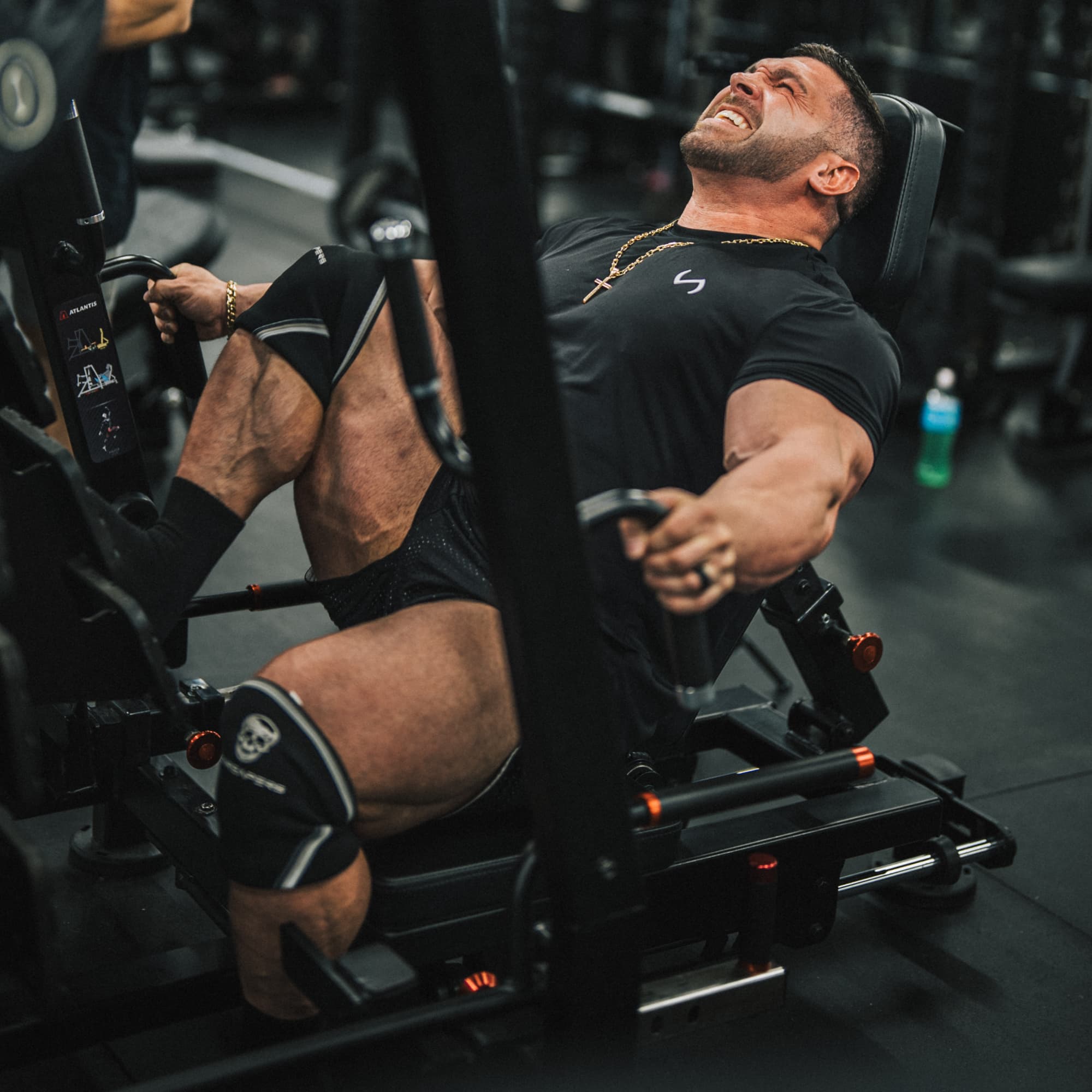 Athlete doing leg press while wearing the black/white 7mm knee sleeves