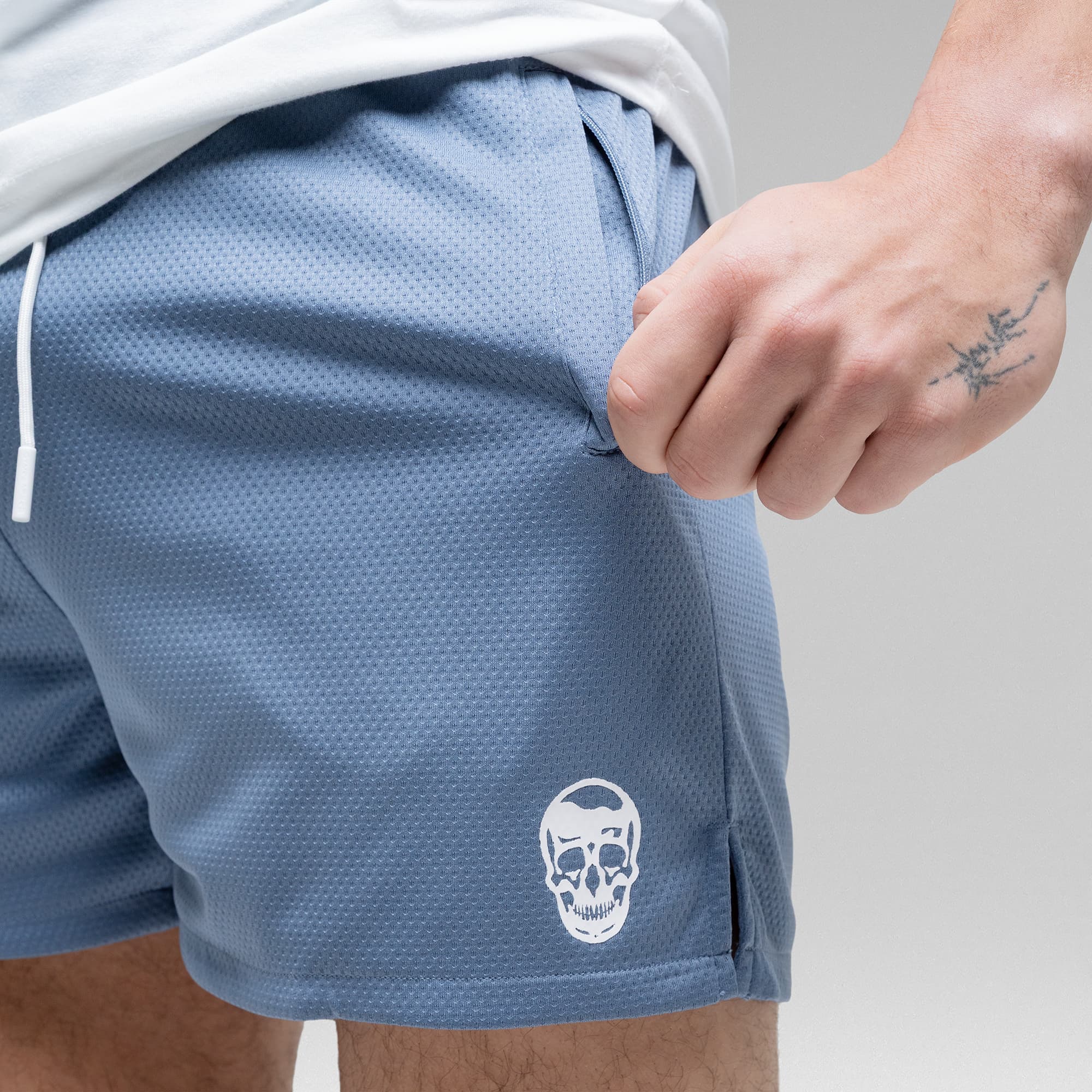 Athlete wearing the Pale Blue Core Skull Mesh Training Shorts detail shot of zipper and logo