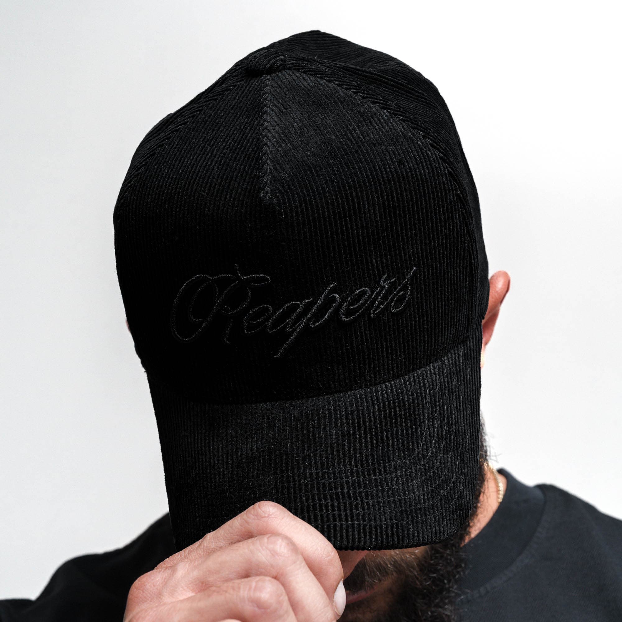 Athlete wearing Corduroy Reapers 5-Panel Hat - Black/Black looking down showcasing logo