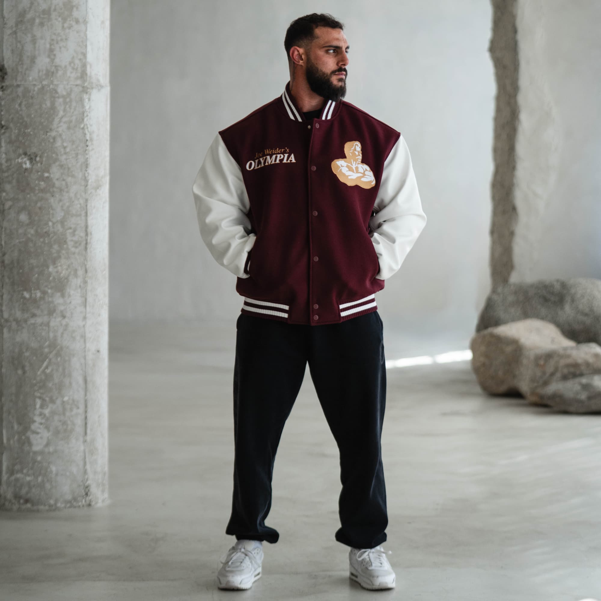 Lifestyle back view of model wearing the Royal O Varsity Jacket, showcasing the bold embroidered Olympia crest design.