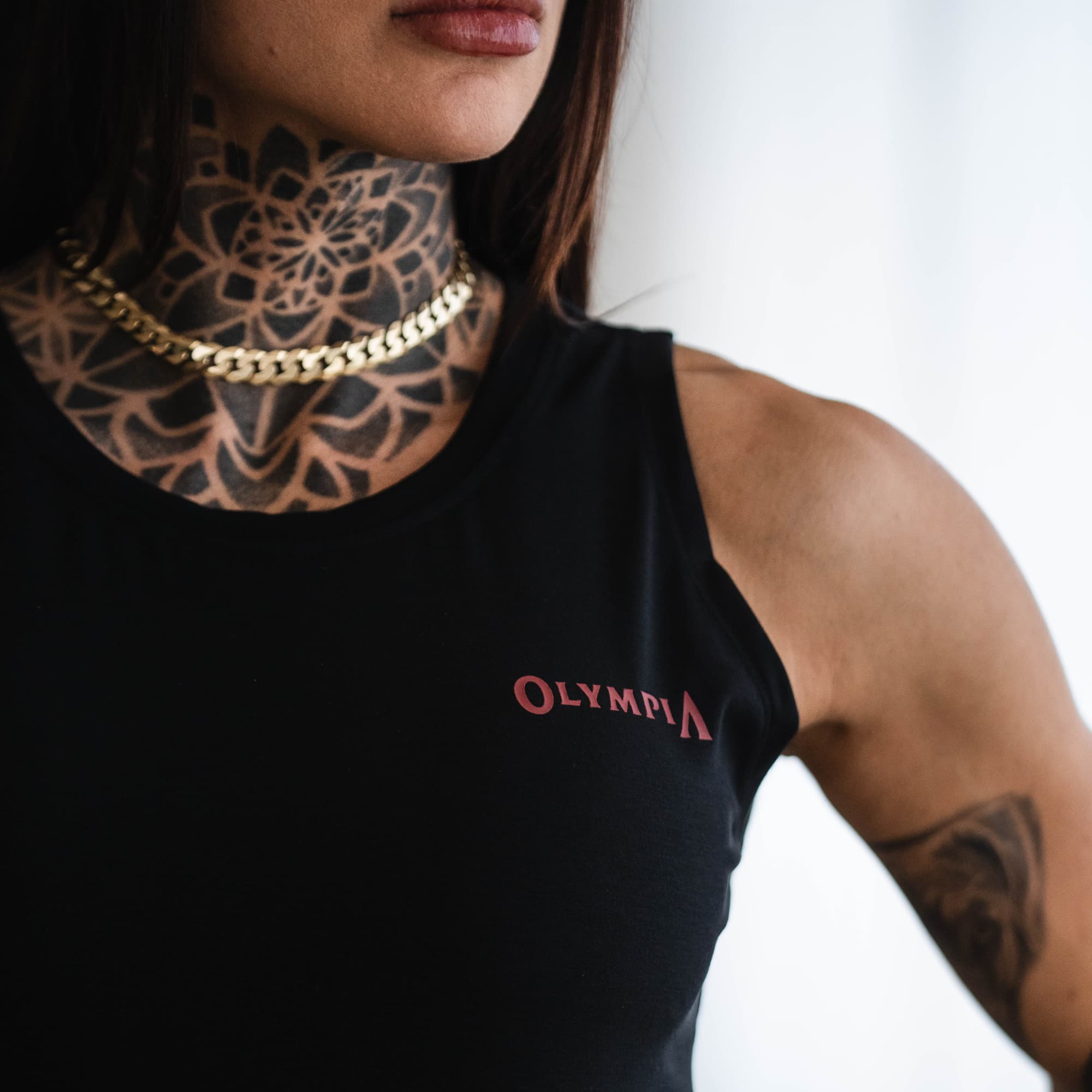 Close-up of Olympia Full Length Training Tank chest logo on model.