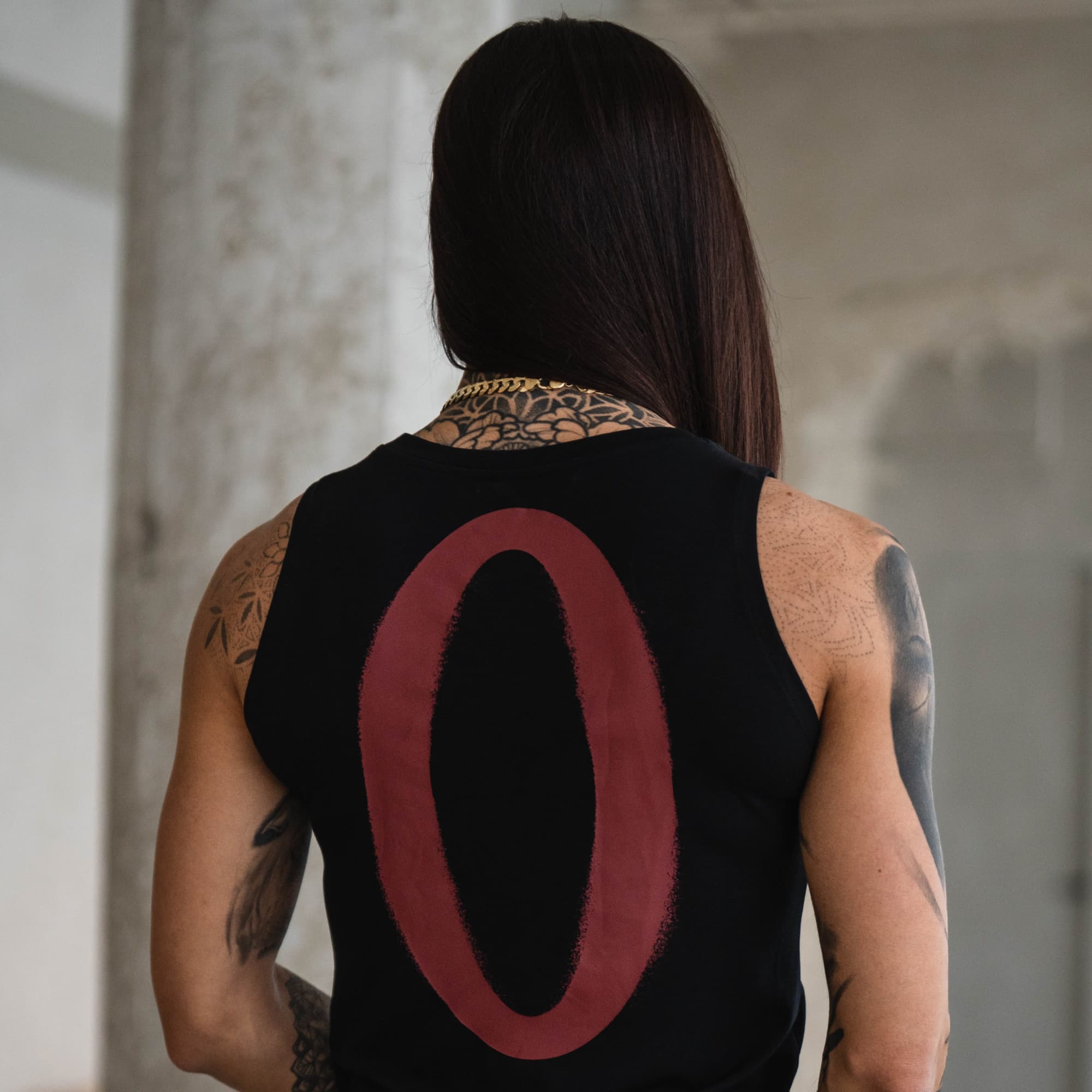 Model wearing Olympia Full Length Training Tank, back view with oversized “O” graphic.