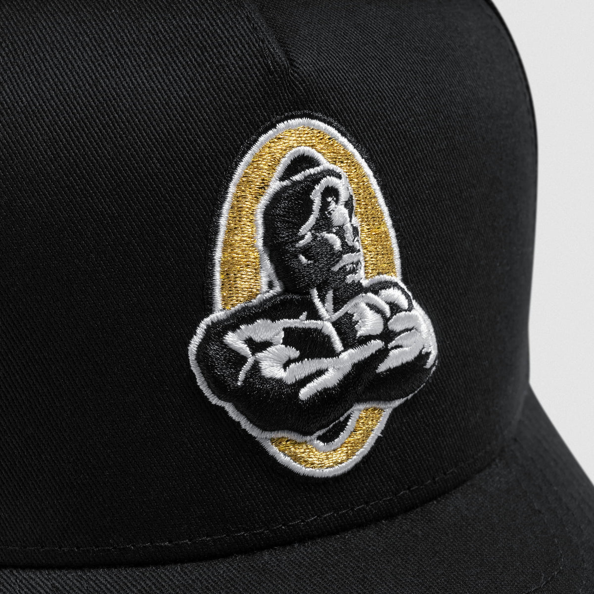 Close up of the Champions Gold Olympia logo on the Champions Gold 5-Panel Hat