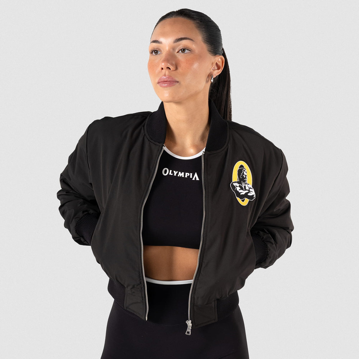 Champions Gold Crop Bomber Jacket | Front facing view of model, with hands and pockets and jacket unzipped