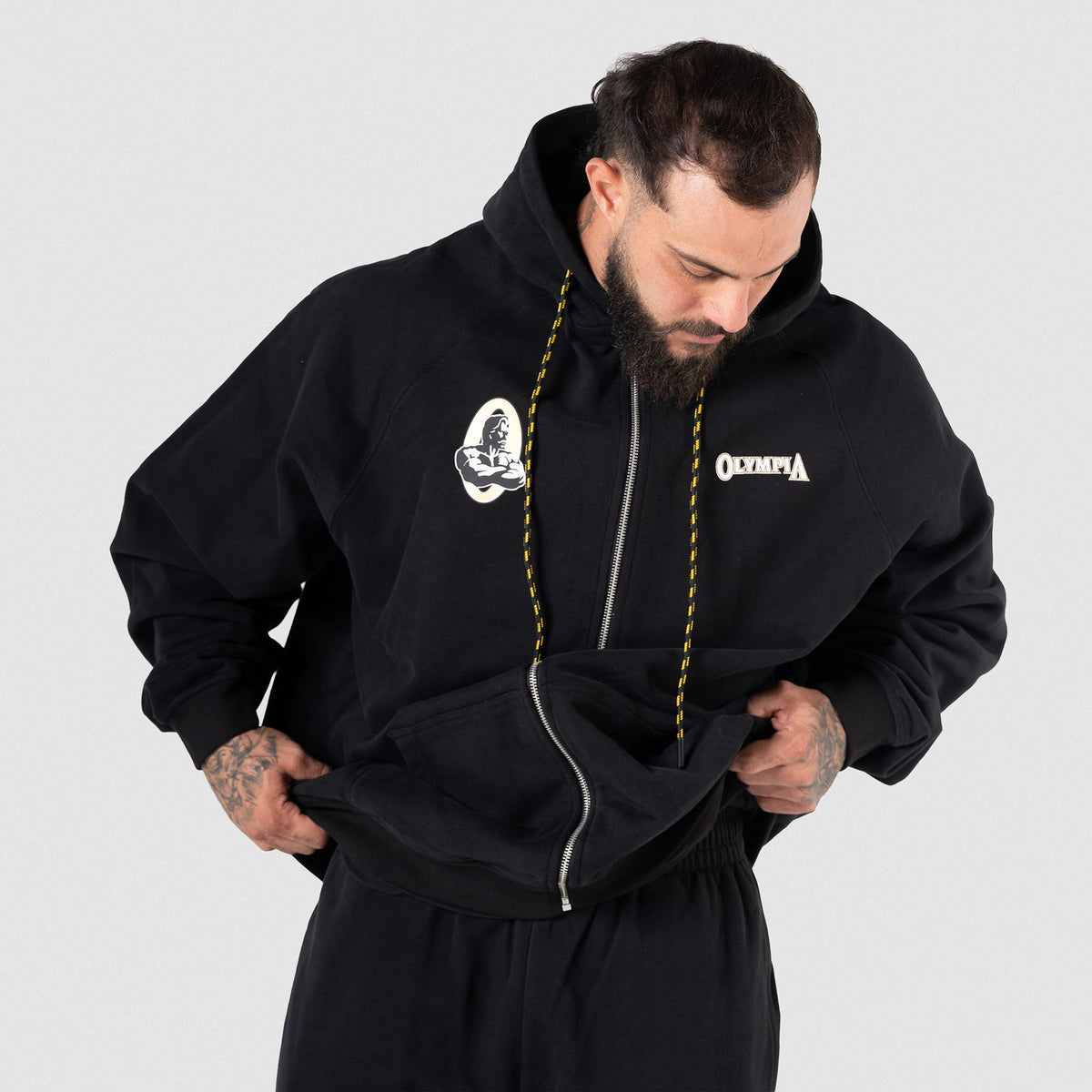 Champions Gold Zip-Up Hoodie | Male model wearing fully zipped black hoodie, showcasing black and gold striped drawstrings and chest graphics
