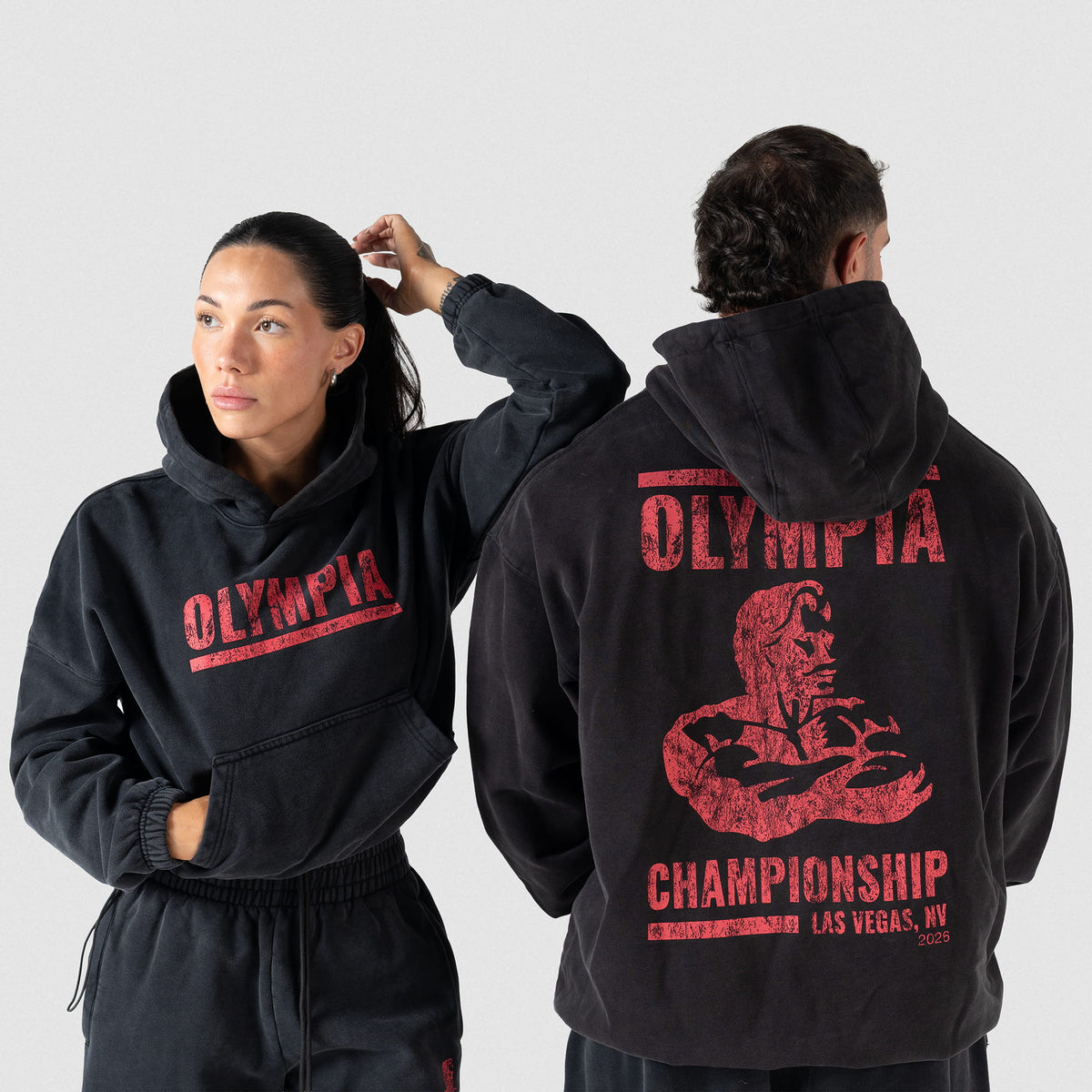 Championship Crop Hoodie | Female model facing forward and Male model facing away from camera to show the front and back logos of the Championship hoodies