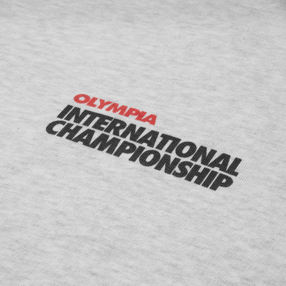 International Division Hoodie | Close up view of chest logo that says "Olympia" in red text and "International Championship" in black text