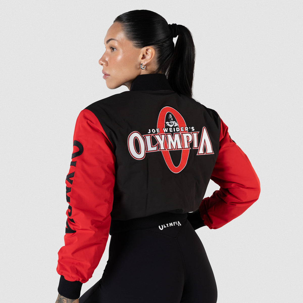 Signature Crop Bomber Jacket | Back view of Model wearing the Jacket with black torso and red sleeves, featuring the Joe Weider's Olympia classic logo