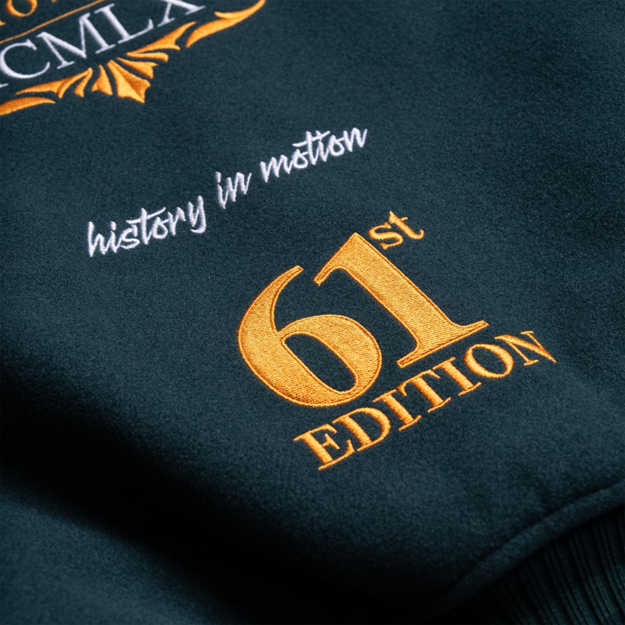 Close-up of gold embroidered “61st Edition” and white “history in motion” text on the back of the jacket.