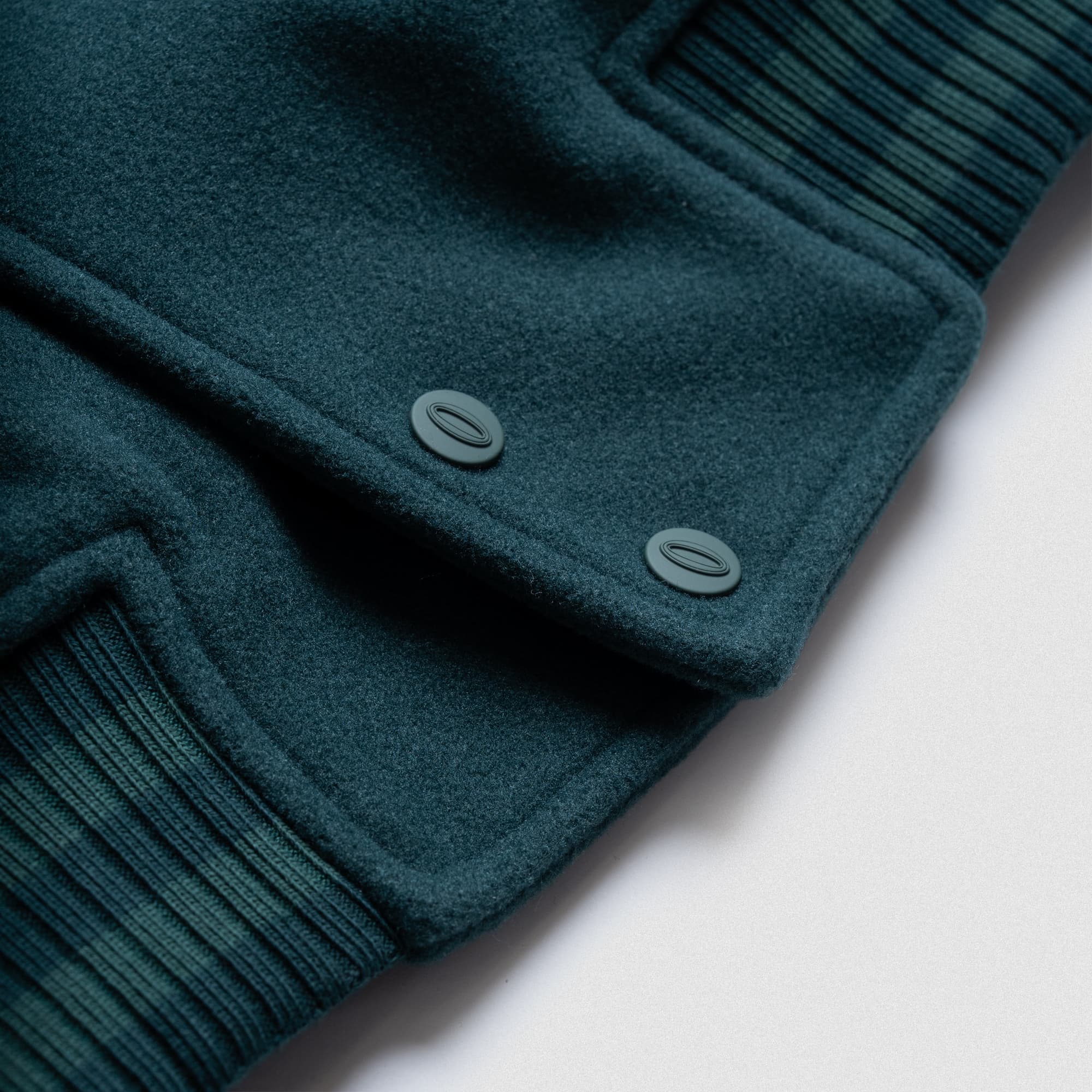 Detail of green snap buttons and ribbed hem on the Olympia Champion Made Varsity Jacket.