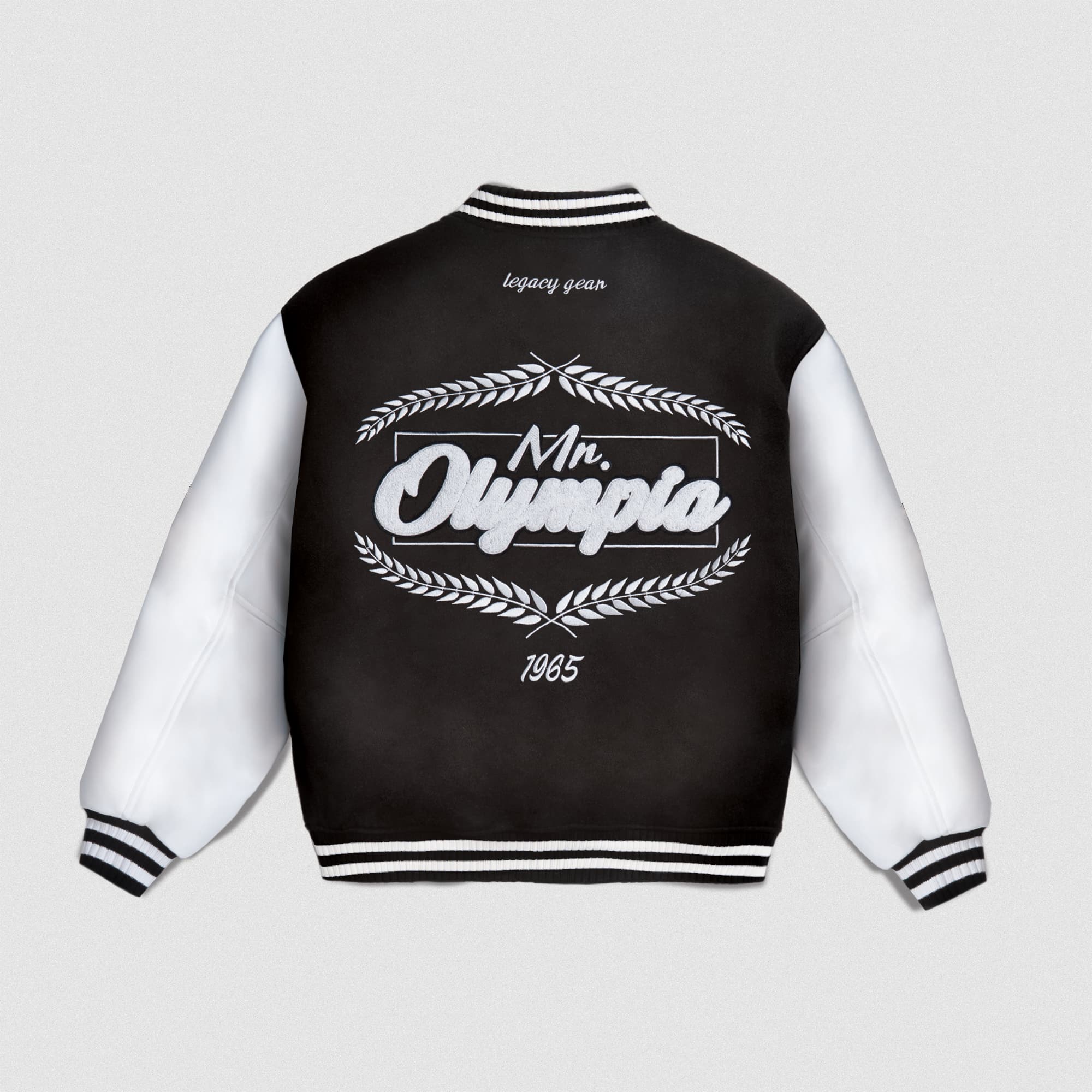 Back view of Mr. O Varsity Jacket with black body, white sleeves, and large embroidered “Mr. Olympia 1965” wreath graphic.