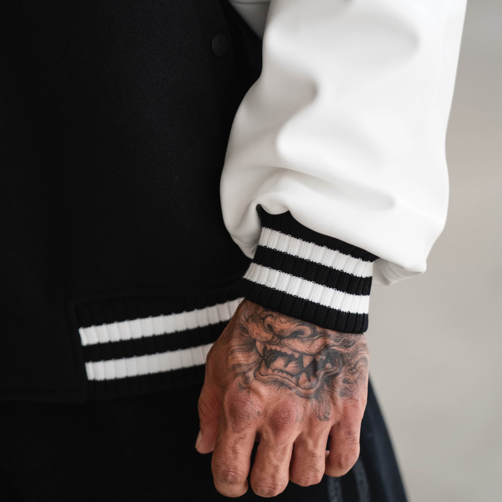 Close-up of striped ribbed cuff and white sleeve on Mr. O Varsity Jacket.