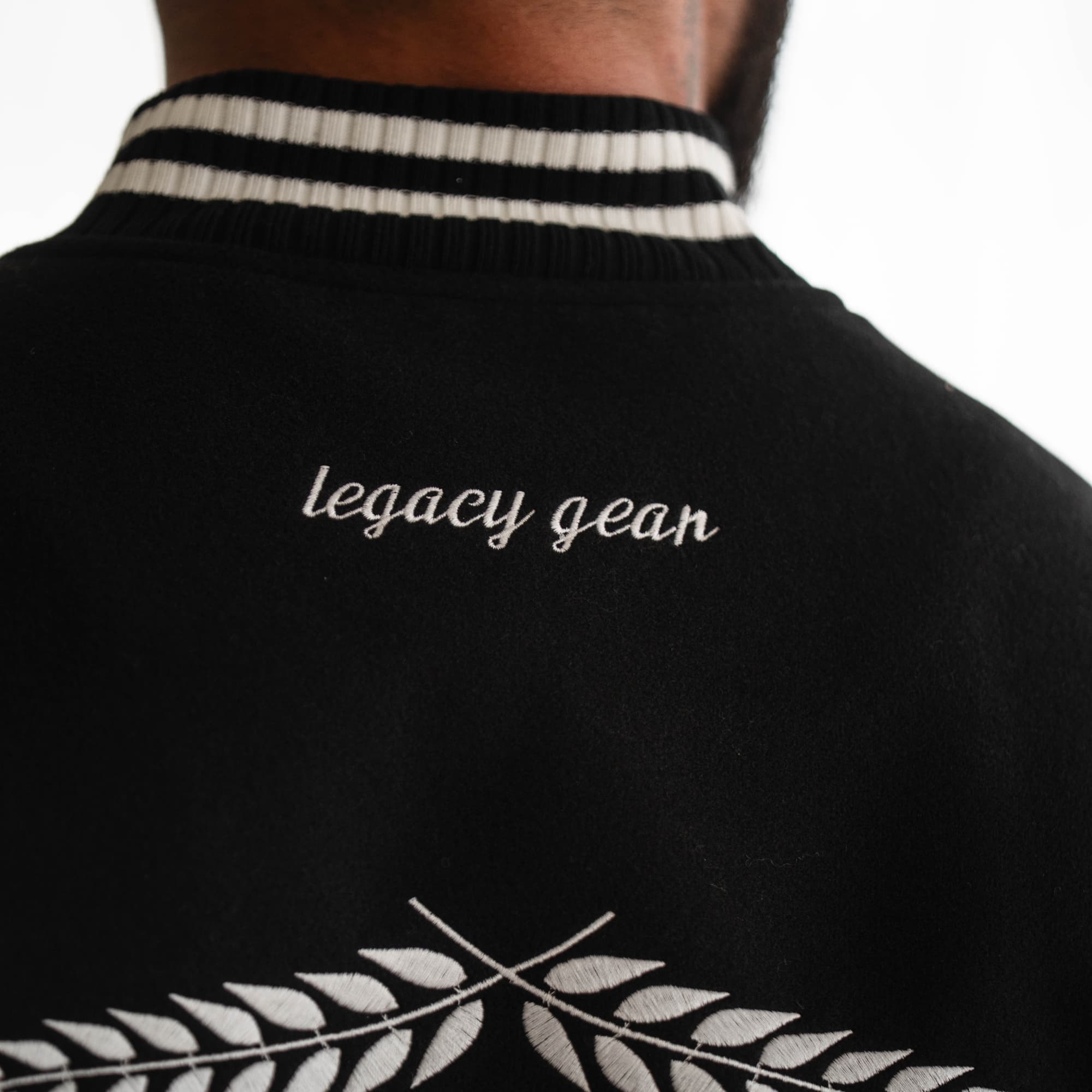 Close-up of “legacy gear” embroidery detail on back collar of Mr. O Varsity Jacket.